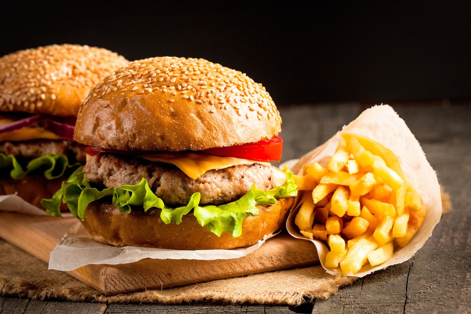 Close-up photo of home made hamburger with beer made of beef, onion, tomato, lettuce, cheese and spices. Fresh burger closeup on wooden rustic table with potato fries and chips.